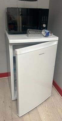 un petit réfrigérateur surmonté d'un micro-ondes