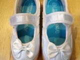 pair of white shoes with bows on them sitting on a wooden floor