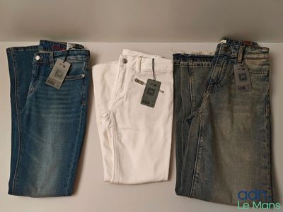 trois paires de jeans pour homme suspendues à un portant