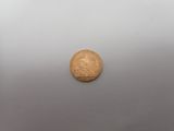 an old gold coin sitting on top of a white surface