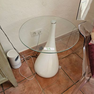 une table en verre sur laquelle est posé un vase blanc