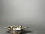 a silver bowl and spoon on a table with a gray background