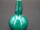 a green glass vase sitting on a black surface