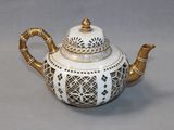 a white and gold teapot on a gray surface