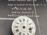 horloge avec des chiffres romains, exposée devant une enseigne « ka - mondo »