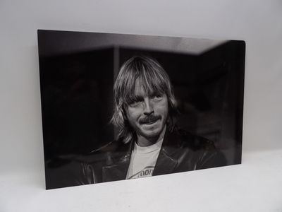 photographie en noir et blanc d'un homme aux cheveux longs portant une veste en cuir