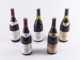 six bottles of wine are lined up in a row on a white surface