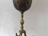 une bouilloire en laiton ancien posée sur un support, surmontée d'une théière