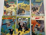 six comics of different sizes and colors are on a table