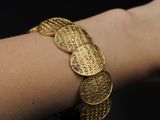 a close up of a person ' s arm with a gold bracelet on it