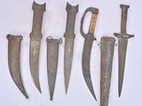several old knives are lined up on a white surface