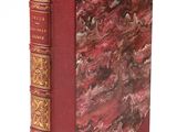 un vieux livre à la couverture rouge posé sur une surface blanche