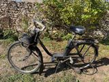un vélo garé dans l'herbe près d'un mur de pierre
