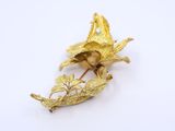 an image of a gold brooch with leaves and flowers on it