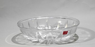 un saladier en verre et une assiette posés sur une surface blanche