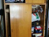 une armoire pleine de vêtements et un sac par terre