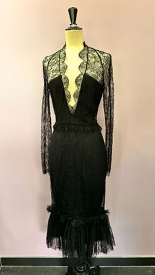 a black dress on a mannequin stand in front of a pink wall