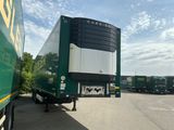 un semi-remorque vert garé sur un parking avec d'autres semi-remorques