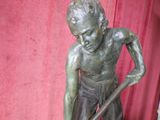 a bronze statue of a boy with a stick in his hand
