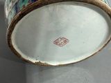 a vase with a lid sitting on a table next to a plate