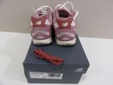 purple and white new balance shoes on a box with a red shoelacer