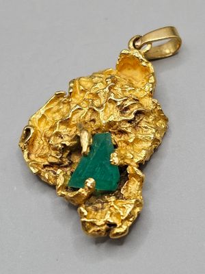 un gros plan d'un pendentif en or orné d'une pierre verte