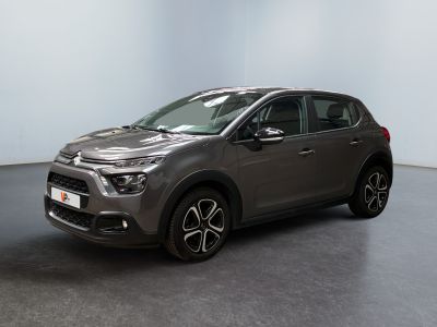 Une voiture grise est garée dans une pièce aux murs blancs.