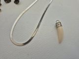 a necklace with a tooth on it next to some other items