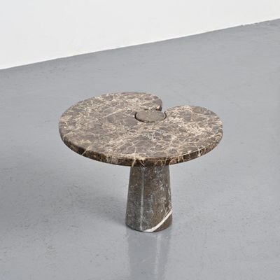 une table en marbre au plateau circulaire posée sur un sol gris