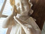 a statue of a little girl holding a piece of paper in her hands