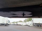 many semi trucks parked under a bridge in a parking lot