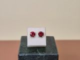 a pair of red sapphire earrings sitting on top of a marble block