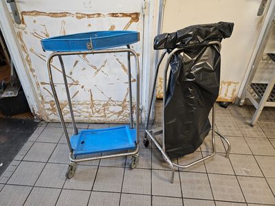 a blue cart sitting next to a black bag on a tiled floor