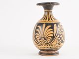 a black and gold vase sitting on a white surface