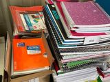 a stack of books on a desk next to a pile of binders