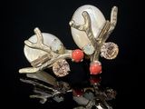 paire de boucles d'oreilles en argent et corail sur fond noir avec reflets