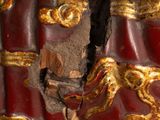 a close up of a red and gold vase with a crack in it