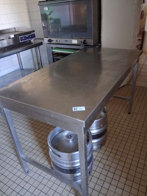 a stainless steel table with kegs on it in a kitchen