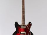 a red and black electric guitar sitting on top of a white surface