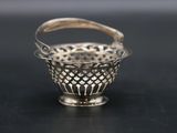 a small silver basket with a handle on a black surface