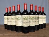 six bottles of red wine lined up on a wooden table