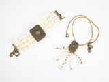 two pieces of jewelry are laying on a white surface