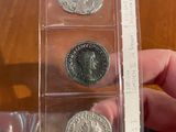 three silver coins in a clear plastic case on top of a wooden table