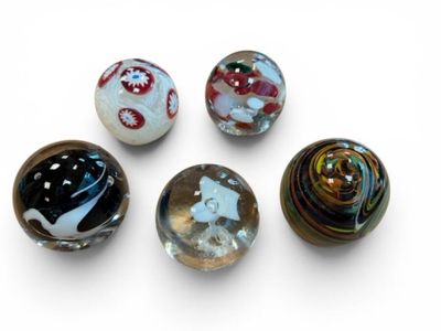 six glass marbles sitting on top of each other on a white surface