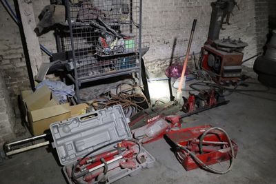 un tas d'outils dans une pièce où se trouve une cage accrochée au mur