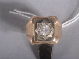 a gold ring with a diamond in it on a white surface