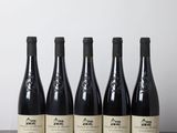 cinq bouteilles de vin sont posées sur une table devant un mur blanc