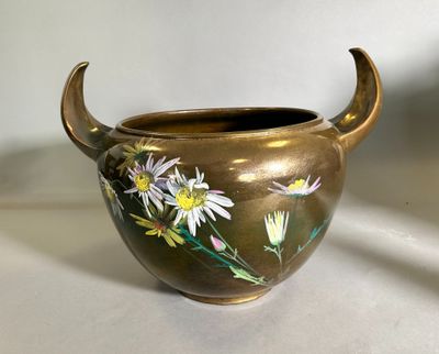 un vase en or orné de fleurs peintes, posé sur une table