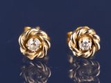 une paire de boucles d'oreilles en or jaune et diamants sur un fond bleu