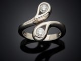 a close up of a ring with two diamonds on a black surface